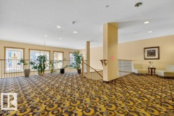Spacious upper-level landing with patterned carpet flooring, recessed lighting overlooking the main entrance below. - 