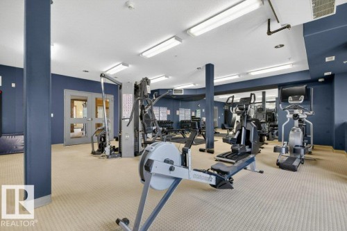 Fitness center featuring a rowing machine, various exercise equipment, and mirrored wall panels - 223 10121 80 Avenue, Edmonton, AB - Indoor Photo Showing Gym Room