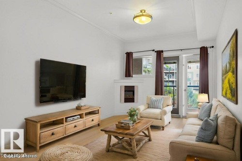 Living area featuring brand new vinyl plank flooring,  crown molding, a built-in electric fireplace and French doors leading to the balcony. This photo has been virtually staged. - 223 10121 80 Avenue, Edmonton, AB - Indoor Photo Showing Living Room