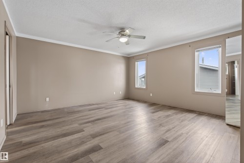 Spacious interior room featuring wood-finish flooring, a ceiling fan, dual windows, and neutral wall tones - 3917 52 Avenue, Cold Lake, AB - Indoor Photo Showing Other Room