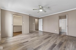 Spacious room featuring wood-finish flooring, a ceiling fan with integrated lighting, bi-fold closet doors, and access to an en-suite bathroom with a built-in vanity and tub/shower combination - 