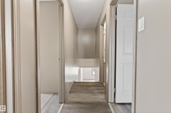 Hallway featuring wood-finish flooring, light-toned walls, and multiple doorways - 