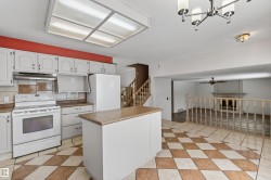 Kitchen featuring white cabinetry, a built-in range, a matching refrigerator, a center island with a countertop, and checkerboard floor tiling - 