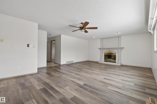 Spacious room featuring wood-finish flooring, a decorative fireplace with an ornate mantel, and a ceiling fan - 3917 52 Avenue, Cold Lake, AB - Indoor Photo Showing Living Room With Fireplace