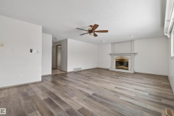 Spacious room featuring wood-finish flooring, a decorative fireplace with an ornate mantel, and a ceiling fan - 