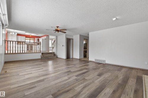 Spacious interior featuring wood-finish flooring, a ceiling fan, and a half-wall with balusters separating levels - 3917 52 Avenue, Cold Lake, AB - Indoor Photo Showing Other Room