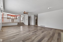 Spacious interior featuring wood-finish flooring, a ceiling fan, and a half-wall with balusters separating levels - 