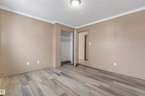Spacious room featuring wood-finish flooring, neutral-toned walls, and white crown molding - 3917 52 Avenue, Cold Lake, AB - Indoor Photo Showing Other Room