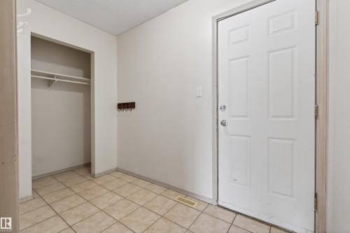White six-panel entry door with polished chrome hardware, complemented by beige ceramic tile flooring - 3917 52 Avenue, Cold Lake, AB - Indoor Photo Showing Other Room