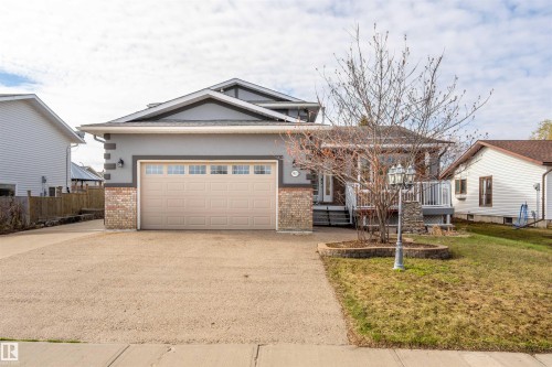 Exterior featuring a two-car garage with a panel door, decorative window inserts, and stucco siding - 3917 52 Avenue, Cold Lake, AB - Outdoor