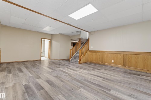 Spacious room featuring wood-finish flooring, light-toned walls, and wood paneling along the lower wall - 3917 52 Avenue, Cold Lake, AB - Indoor Photo Showing Other Room
