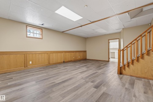 Spacious room featuring wood-finish flooring and a light wood wainscoting accent wall - 3917 52 Avenue, Cold Lake, AB - Indoor
