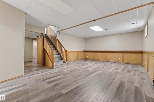Expansive finished space featuring wood-finish flooring, light wood wainscoting, and a full staircase with wood railings - 3917 52 Avenue, Cold Lake, AB - Indoor