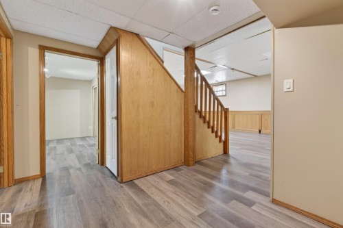 Lower level featuring wood-finish flooring, a wood-paneled staircase, and a drop ceiling - 3917 52 Avenue, Cold Lake, AB - Indoor Photo Showing Other Room