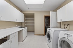 Utility room featuring extensive white cabinetry, a built-in sink, a long countertop, and recessed ceiling lighting - 