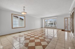 Spacious interior featuring checkerboard tile flooring, large bay window, and a decorative entry door with sidelights - 