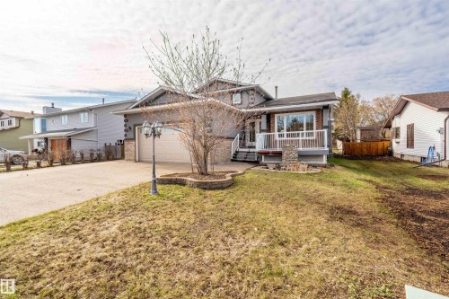 Split-level property featuring a front deck with white railings, a stone accent wall, and large windows - 3917 52 Avenue, Cold Lake, AB - Outdoor With Deck Patio Veranda