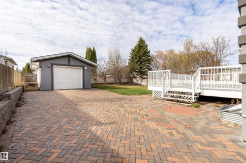 Paver patio and driveway with a detached garage featuring a white overhead door - 3917 52 Avenue, Cold Lake, AB - Outdoor