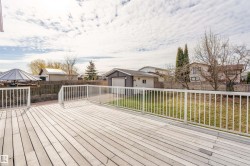 Spacious deck with composite decking and white railing overlooking a fenced yard and detached garage - 