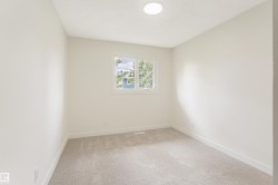 Neutral-toned room featuring a single window, light-colored walls, and gray carpet flooring - 