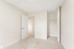 Bright room featuring neutral wall paint, light-colored carpet flooring, white baseboards, and a modern interior door with brushed nickel hardware - 