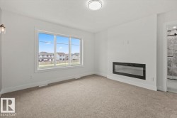 Carpeted room featuring a large multi-pane window, built-in electric fireplace, and flush-mount ceiling light - 