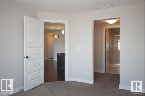 Neutral-toned room with carpeted flooring, featuring a five-panel interior door with brushed nickel hardware - 531 5151 Windermere Boulevard, Edmonton, AB - Indoor