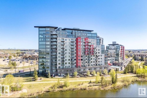 Contemporary high-rise building featuring a glass and panel facade with red accents - 531 5151 Windermere Boulevard, Edmonton, AB - Outdoor With Body Of Water With Facade With View