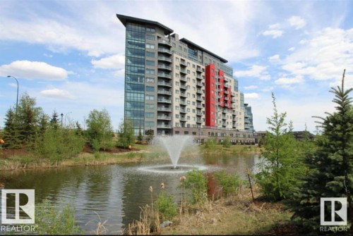 Modern high-rise building featuring a striking red facade accent, glass curtain wall elements, and private balconies - 531 5151 Windermere Boulevard, Edmonton, AB - Outdoor With Body Of Water With Facade
