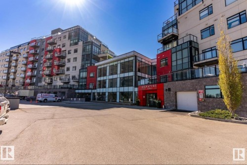 Contemporary multi-story building featuring a red and grey exterior, extensive glass paneling, and private balconies with glass railings - 531 5151 Windermere Boulevard, Edmonton, AB - Outdoor With Facade