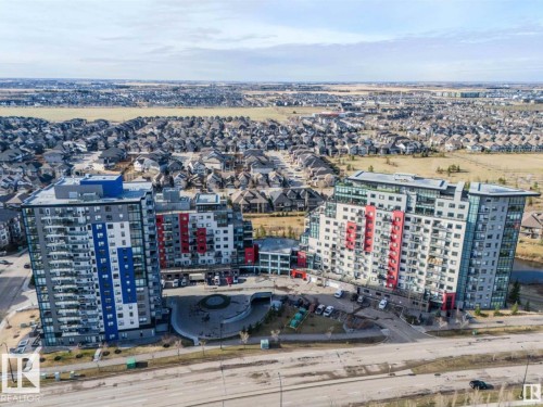 Modern multi-story buildings featuring vibrant red and blue exterior panels, multiple balconies, and a paved circular drive - 531 5151 Windermere Boulevard, Edmonton, AB - Outdoor With View