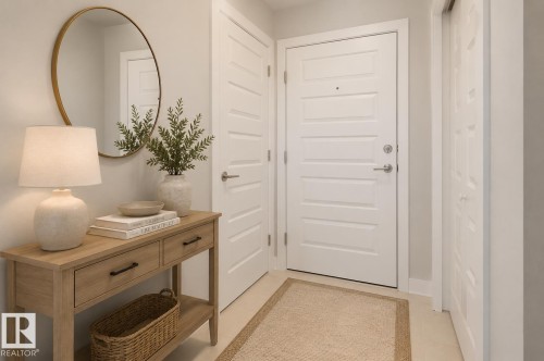 Entryway featuring a white paneled door with brushed nickel hardware, light-toned flooring, and a console table with drawer storage - 531 5151 Windermere Boulevard, Edmonton, AB - Indoor Photo Showing Other Room