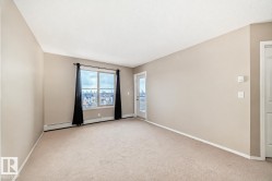 Carpeted room featuring a large window, a glass-paneled door, and neutral-toned walls - 