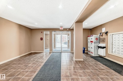 Building foyer with tile flooring, recessed lighting, and a mail area featuring individual mailboxes and a parcel locker - 404 12025 22 Avenue, Edmonton, AB - Indoor Photo Showing Other Room