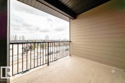Private balcony featuring durable composite decking, sleek black metal railings, and neutral-toned siding - 