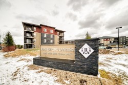 Rutherford Landing entry monument featuring a stacked stone base and a white sign with a diamond-shaped emblem - 
