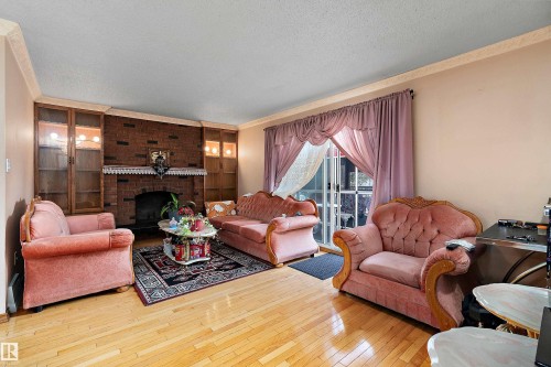 Living area featuring wood-finish flooring and a brick-faced fireplace - 15907 101 Street, Edmonton, AB - Indoor Photo Showing Living Room