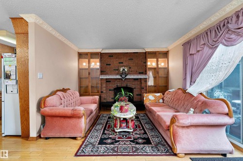 Brick fireplace with built-in cabinetry, wood-finish flooring, and crown molding - 15907 101 Street, Edmonton, AB - Indoor Photo Showing Living Room