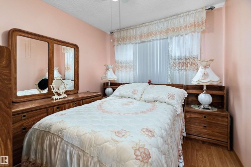 Bedroom featuring wood-finish flooring, light peach walls, and a window with vertical blinds and decorative valance - 15907 101 Street, Edmonton, AB - Indoor Photo Showing Bedroom