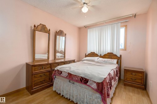 Bedroom featuring a ceiling fan with integrated lighting, wood-finish flooring, and a large window with vertical blinds - 15907 101 Street, Edmonton, AB - Indoor Photo Showing Bedroom