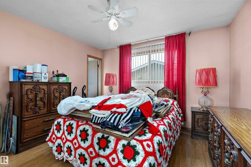 Bedroom featuring wood-finish flooring, a ceiling fan, and a window with vertical blinds and drapes - 15907 101 Street, Edmonton, AB - Indoor Photo Showing Bedroom