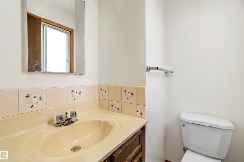 Bathroom vanity featuring an integrated sink, chrome faucet, and patterned tile backsplash - 15907 101 Street, Edmonton, AB - Indoor Photo Showing Bathroom