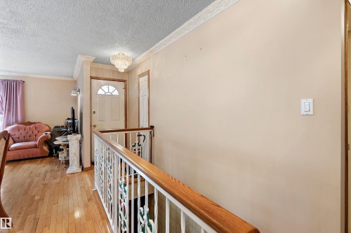 Entryway featuring a white paneled door with an arched glass insert, hardwood flooring, and a crystal chandelier - 15907 101 Street, Edmonton, AB - Indoor Photo Showing Other Room