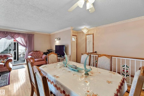 Dining area featuring hardwood-finish flooring, a decorative railing, and crown molding - 15907 101 Street, Edmonton, AB - Indoor Photo Showing Dining Room