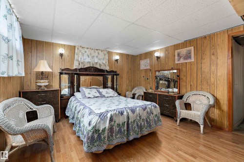 Room featuring wood-finish paneling, wood-finish flooring, and a drop ceiling - 15907 101 Street, Edmonton, AB - Indoor Photo Showing Bedroom