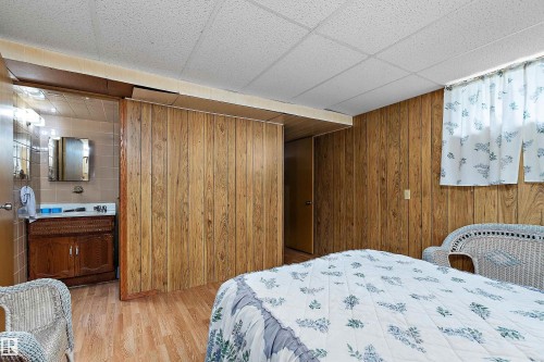 Interior space featuring wood-finish wall paneling, wood-finish flooring, and a drop ceiling - 15907 101 Street, Edmonton, AB - Indoor Photo Showing Bedroom
