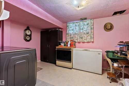Utility room featuring an overhead light fixture, a window with curtains, and vinyl flooring - 15907 101 Street, Edmonton, AB - Indoor Photo Showing Laundry Room