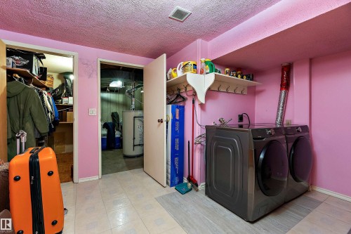 Dedicated laundry area featuring modern washer and dryer units, tiled flooring, and an overhead shelf with hooks for organization - 15907 101 Street, Edmonton, AB - Indoor Photo Showing Laundry Room