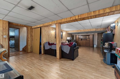 Lower-level recreation room featuring wood-finish flooring and extensive wood paneling - 15907 101 Street, Edmonton, AB - Indoor
