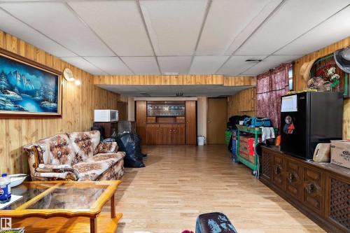 Recreation room featuring wood-finish wall paneling, a dropped ceiling, and wood-finish flooring - 15907 101 Street, Edmonton, AB - Indoor
